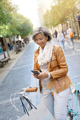 Senior woman in town with bike, talking on phone