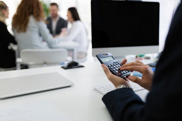 Businessman analyzing investment charts with calculator on office desk