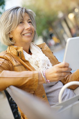 Senior woman in town using digital tablet