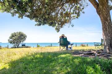 A women sitting under the tree and enjoying the beautiful landscape view of the ocean in New...