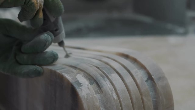 Worker engraving marble with electrical engraver, visible stone dust, closeup