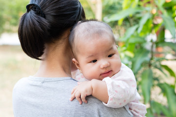 Mother holding adorable baby daughter in her arms