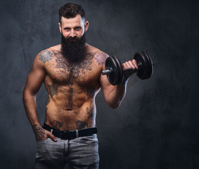 Fototapeta na wymiar Shirtless muscular, bearded male holds dumbbell.