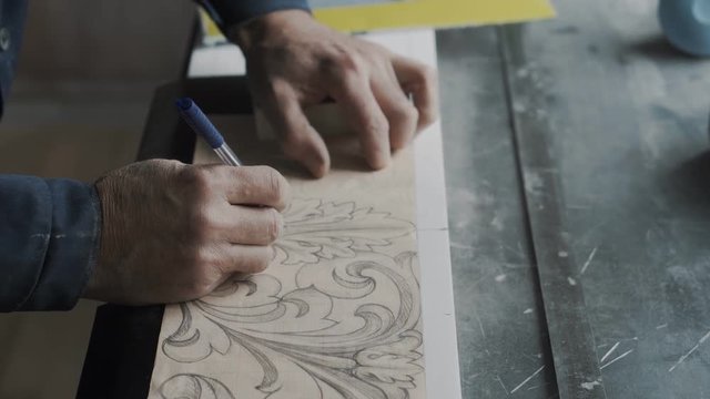 Worker without two phalanges on his arm, he traces lines on the fluted paper using a pen and a carbon paper, translates the picture to a stone 