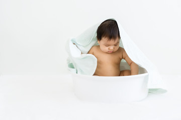 Portrait of adorable baby sitting in the basin for shower, indoors