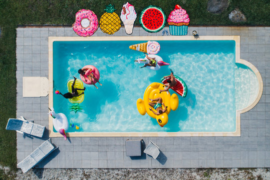 Group of friends having fun in the pool with different air beds