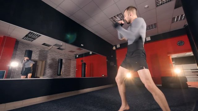A boxer trains by himself near a gyms mirror. 