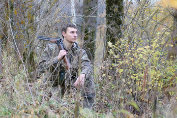 Man in camouflage and with guns in a forest belt on a spring hunt