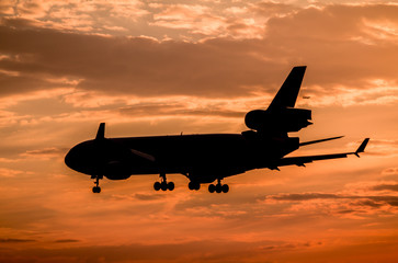 Naklejka na ściany i meble Airplane landing at sunset