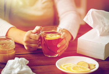 close up of ill woman drinking tea with lemon