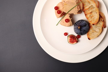 foie gras with croutons, figs and redcurrant. in a white plate, on a marble table