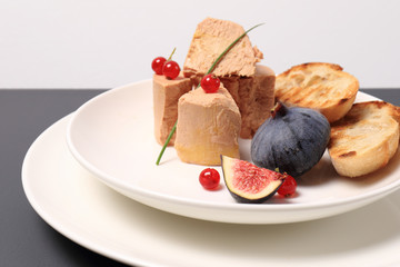 foie gras with croutons, figs and redcurrant. in a white plate, on a marble table. copy space