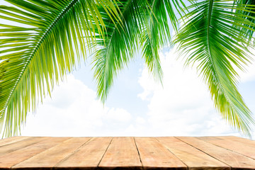 Empty wood table top with the palm leaves on sky  background. For montage product display or design key visual layout.