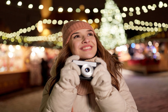 happy young woman with camera at christmas market