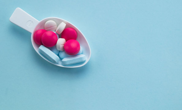 colorful color pills in the tablespoon on blue background