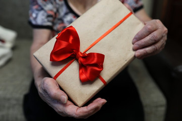 gift box with red bow in grandmother hands