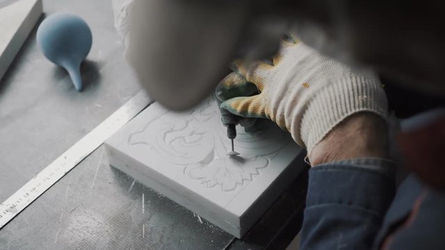 Sculptor cuts out of the marble slab a part of the ornament, the drawing on stone is done in advance