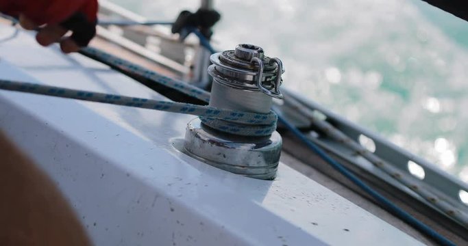 Sailing, man pulling ropes, winding sheets around winches. close-up