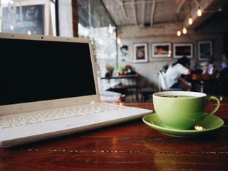 Close up laptop and coffee cup on working table.