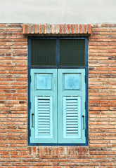 Fototapeta na wymiar Wooden window shutter cyan in a traditional brickwork exterior wall.