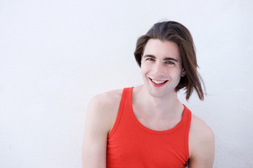 Close up happy young athletic man standing by white wall