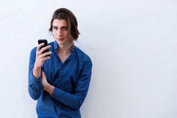 Fototapeta premium Handsome young man standing and holding smart phone