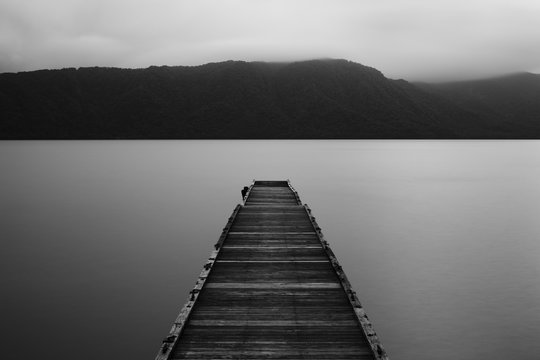 Wooden jetty and flat calm lake, dark low light 