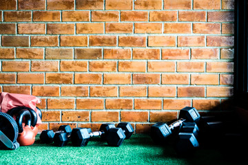 Brick wall with artificial grass and dumbbells on the foreground