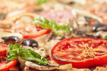 Closeup of pizza with salami, tomatoes and olives