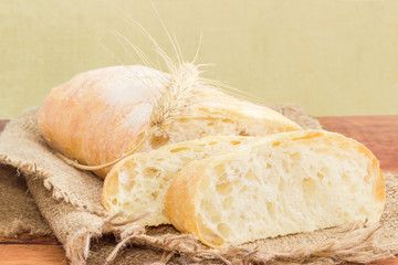 Partly sliced ciabatta with wheat ear on a sackcloth