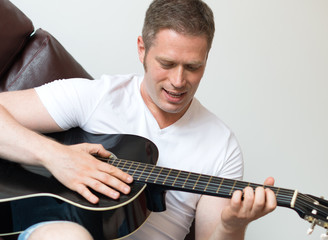 Fototapeta na wymiar Handsome man playing guitar at home.
