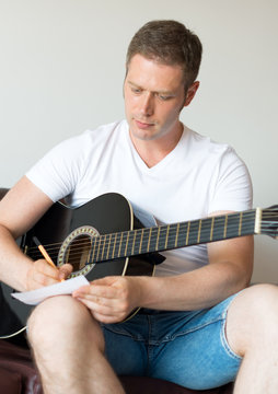 Handsome man compose a song on the guitar.