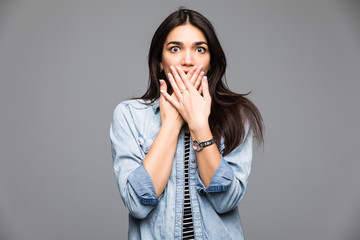 Pretty happy girl covering her mouth over grey background