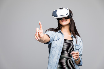 Young woman wearing virtual reality glasses and pointing upwards with her finger with a serious expression