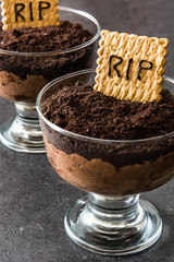 Funny Halloween chocolate mousse with tomb cookie on black stone
