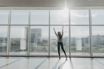 Fototapeta na wymiar Confident woman spreading hands standing at office window, enjoying big city, successful entrepreneur celebrating business success with arms open wide, feeling powerful inspired, rear view