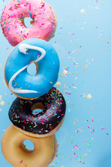flying doughnuts border - mix of multicolored sweet donuts with sprinkles on blue background