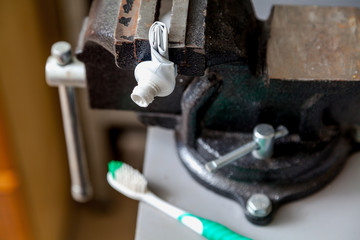 Twisted tube of toothpaste squeezed in bench screw