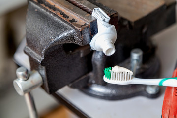 Toothpaste squeezed from tube onto brush squeezed vise