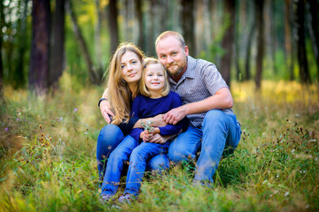 Fototapeta premium .happy family walks in the park, hug each other and look at the camera, the girl is holding a bouquet of wildflowers in her hands
