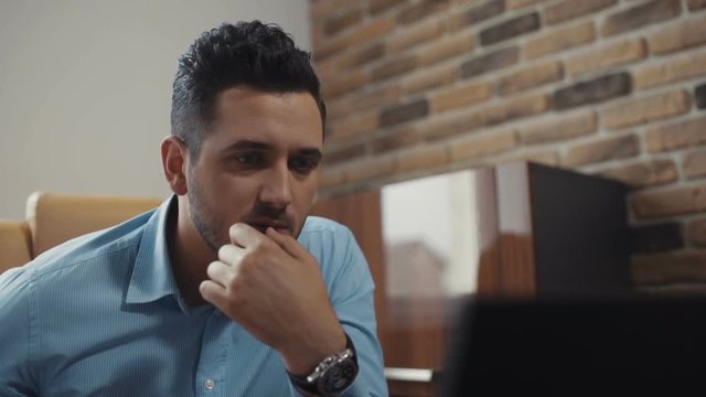 Young attractive man uses a laptop working in the office. Business. Surprised. Shot on RED Epic Camera.