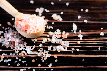Pink and white rock salt in wooden spoon on wood background, selective focus