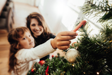 Mother and daughter decorating Christmas tree.