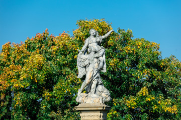 Fototapeta premium Classic statue in a park with blue sky and tree on background