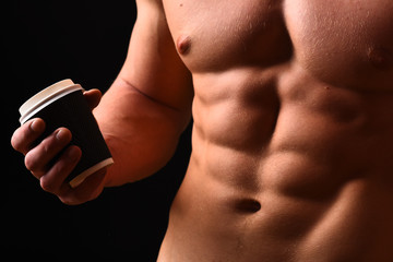 Athletes body in close up, hand holding coffee cup
