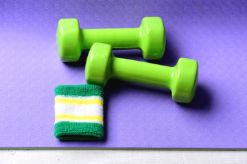 Shaping and fitness. Barbells near white and green hand band