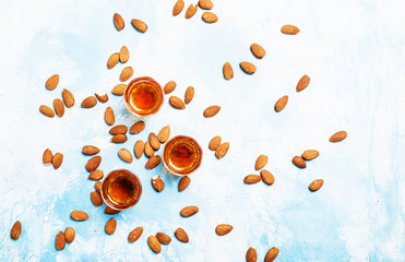 Almond liqueur with nuts on light background, top view
