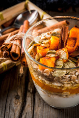 Traditional autumn dishes, spicy pumpkin pie overnight oatmeal with cinnamon, anise and maple syrup. In portioned glasses, on wooden old rustic table. Copy space