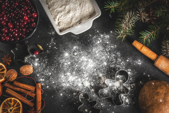 Ingredients for Christmas, winter baking cookies. Gingerbread, fruitcake. Flour, cranberries, dried oranges, cinnamon, spices on a black stone table, top view copy space