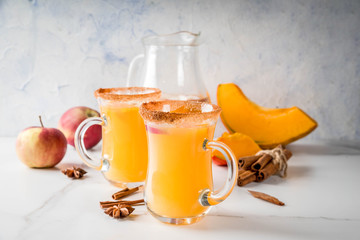 Halloween, Thanksgiving. Traditional autumn, winter drinks and cocktails. Spicy hot pumpkin sangria, with apple, cinnamon, anise. On a white marble table, in glass mugs. Selective focus, copy space
